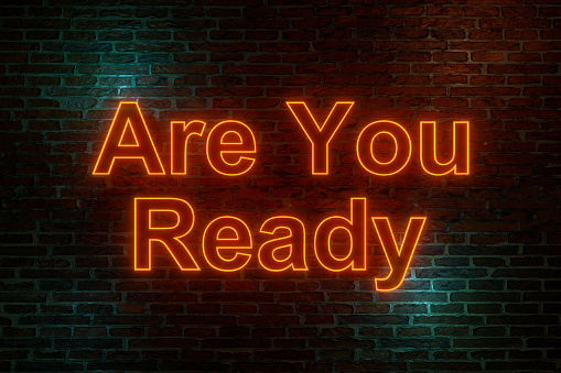 Brick wall at night with the text Are you ready in orange neon letters. Announcement message, motivation, encouragement and inspiration. 3D illustration