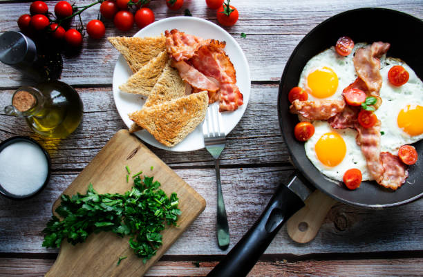 istock Fried eggs with bacon and fresh tomatoes. On a wooden background 1482140361