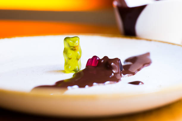 Gummy bears playing on a food table with chocolate sauce.