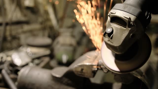 A man worked hard with a steel grinder, close-up in the garage