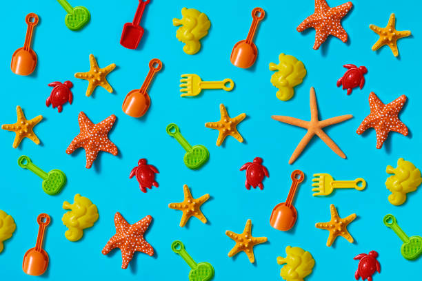some beach shovels and rackets, some sand molds in the shape of seahorses and turtles, and some natural and fake starfish on a blue background