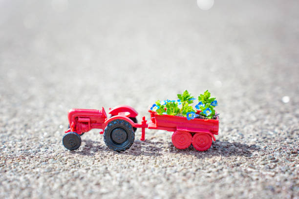 Miniature red tractor transporting a flower bed filled with vibrant spring blooms, embodying the concept of spring landscaping in the city.