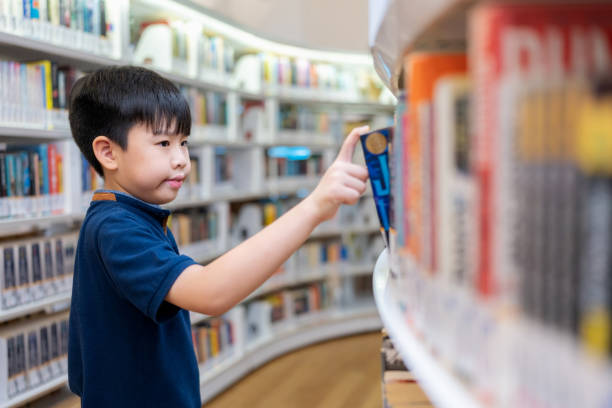 Learning brings about knowledge and acceptance. Asia boy choosing textbook in the library at elementary school. Have fun and enjoy reading fairy tale textbook. Education and learning concept.