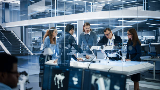 istock Robotics Engineer, Project Manager and Machinery Operators Collaborate on a Robot Canine Project, Standing with Laptop Computer in Scientific Technology Lab. Young Team Developing an AI Robotic Dog. 1482148916