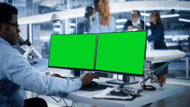 softwareentwickler, der am computer mit green screen mock up display arbeitet. wissenschaftliches labor, technisches forschungszentrum mit spezialisten, die im hintergrund an der entwicklung mobiler roboter arbeiten. - computer lab green office computer stock-fotos und bilder