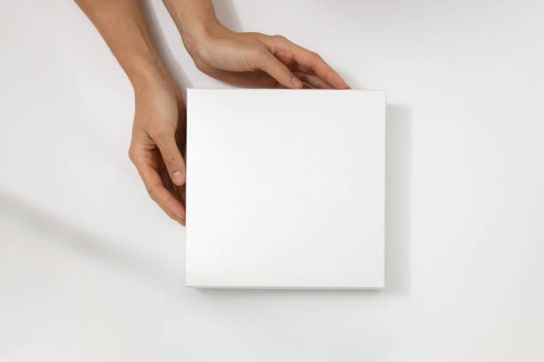 istock Mockup of white box on white background. Hands holding blank cardboard gift 1482149097