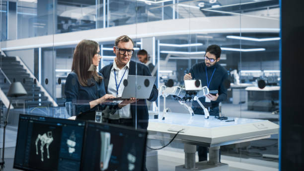 istock Chief Robotics Engineer Having Meeting with Project Manager and Machinery Operators Next to a Mobile Robot Animal Project. Young Team Using Computers, Discussing the Development of an AI Robotic Dog. 1482153219