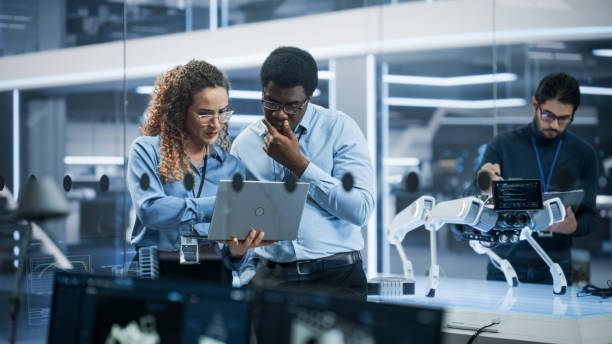 istock Diverse Chief Technology Officer Talking to Software Developer, Discussing Robot Dog Concept in High Tech Research and Development Facility. Professional Industrial Specialists at Work. 1482153297