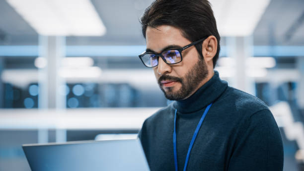 istock Portrait of a Professional Hispanic Man Using Laptop at Work in Research and Development Agency. Young Multiethnic Male Engineer, Developer or Scientist Working in Development Technology Office. 1482153644
