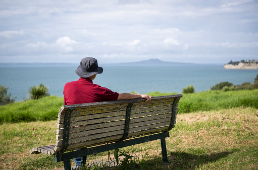 Man enjoying the stunning views of Hauraki Gulf with Rangitoto Island in the distance. Long Bay Coastal Walkway. Auckland.