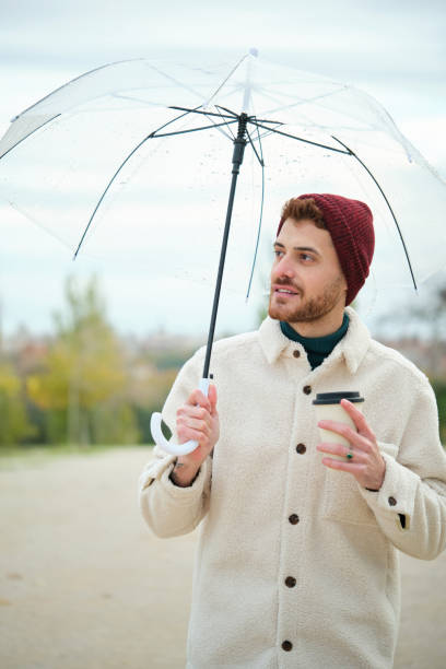 istock Man with a coffee and transparent umbrella in winter. 1482156456