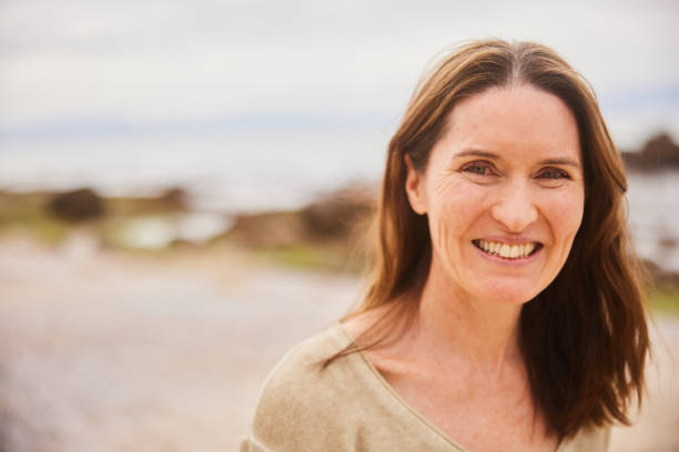 istock Mature woman smiling on a beach on a cloudy day 1482157097
