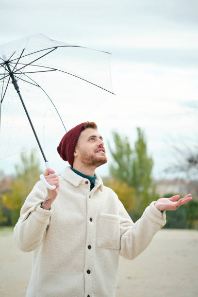 istock Man with a transparent umbrella checking if it is raining in autumn. 1482157306