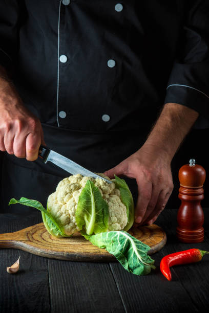 chef profissional está cortando couve-flor em uma cozinha de restaurante. a ideia de uma deliciosa dieta para o café da manhã ou jantar - hotel commercial kitchen organic salad - fotografias e filmes do acervo