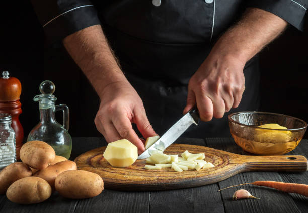 istock The chef cuts raw potatoes into pieces with a knife before preparing breakfast or dinner. Close-up of a cook hands while working in a restaurant kitchen. 1482159609