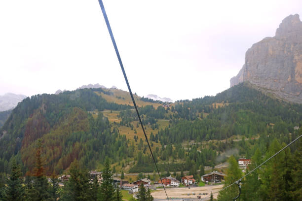 view from the cable car cabin to the village in the mountains and the dolomites in italy. selective focus. - madonna imagens e fotografias de stock