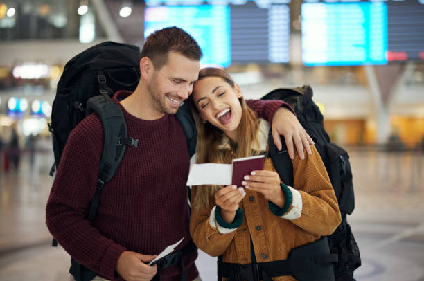 Ticket, travel and couple at airport with passport talking, chatting or laughing at funny joke. Valentines day, comic and happy man and woman in airline lobby with flight documents and boarding pass. boleto, viaje y pareja en el aeropuerto con pasaporte hablando, charlando o riéndose de bromas divertidas. día de san valentín, hombre y mujer cómicos y felices en el vestíbulo de la aerolínea con documentos de vuelo y tarjeta de embarque.