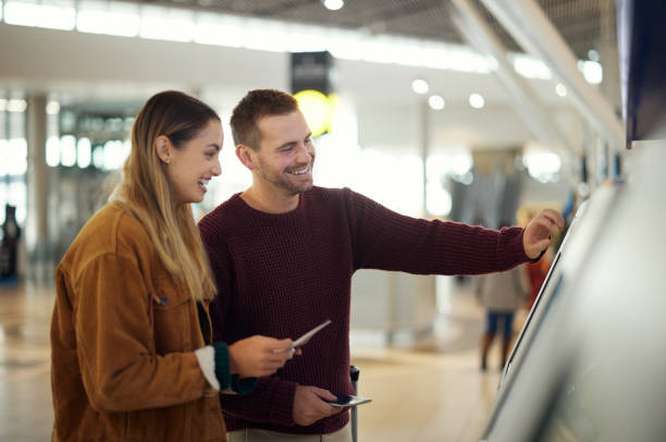 istock Couple in airport typing on self service screen for digital passport identity or flight data to travel on airplane. Smart check, woman or happy man pressing code for on futuristic technology at kiosk 1482169982