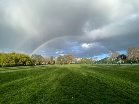 A double rainbow over a grassy field in a London park
