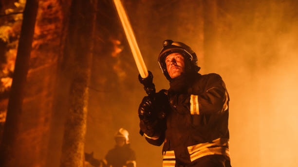 istock Group of Experienced Firefighters Extinguishing a Wildland Brushfire Deep in the Forest. Professional Fireman in Safety Uniform and Helmet Spraying Water from Fire Hose to Battle Dangerous Wildfire. 1482174228