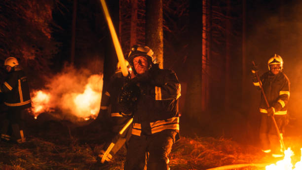 istock Group of Experienced Firefighters Extinguishing a Wildland Brushfire Deep in the Forest. Professional Fireman in Safety Uniform and Helmet Spraying Water from Fire Hose to Battle the Wildfire. 1482174244