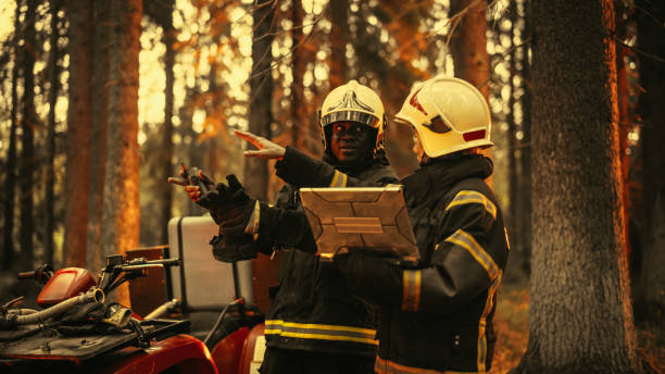 Portrait of Two Professional Firefighters Standing Next to ATV, Discussing the Situation During a Wildland Fire: Female Superintendent Talking with African American Squad Leader, Using Laptop Computer Portrait of Two Professional Firefighters Standing Next to ATV, Discussing the Situation During a Wildland Fire: Female Superintendent Talking with African American Squad Leader, Using Laptop Computer superintendent stock pictures, royalty-free photos & images