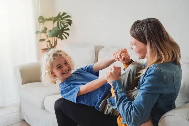 Photo of Happy mother and kid son having fun together at home living room - Family love concept