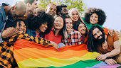Happy diverse people holding lgbt rainbow flag outdoors - Diversity concept - Soft focus on Asian woman young woman face