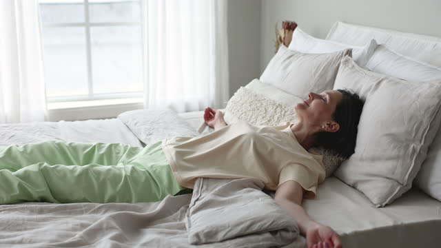 Cheerful excited middle aged older woman falling down in bed