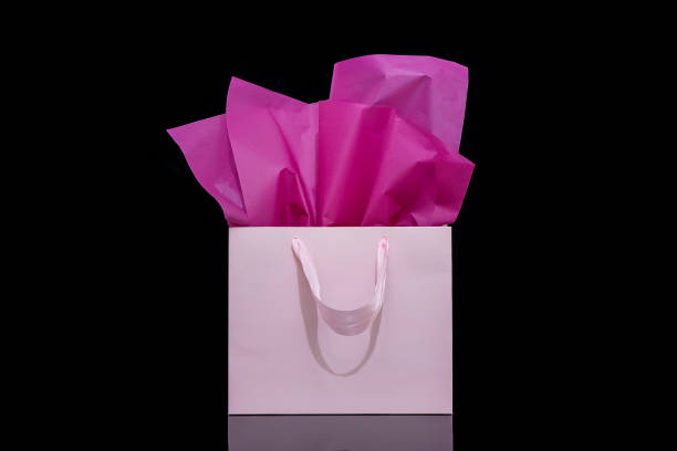 istock Craft paper gift bag with tissue paper isolated on a black background 1482180352