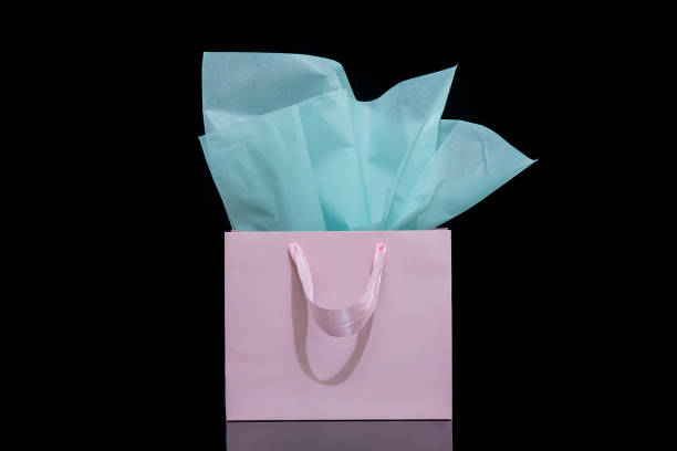 istock Craft paper gift bag with tissue paper isolated on a black background 1482180358