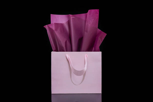 istock Craft paper gift bag with tissue paper isolated on a black background 1482180384