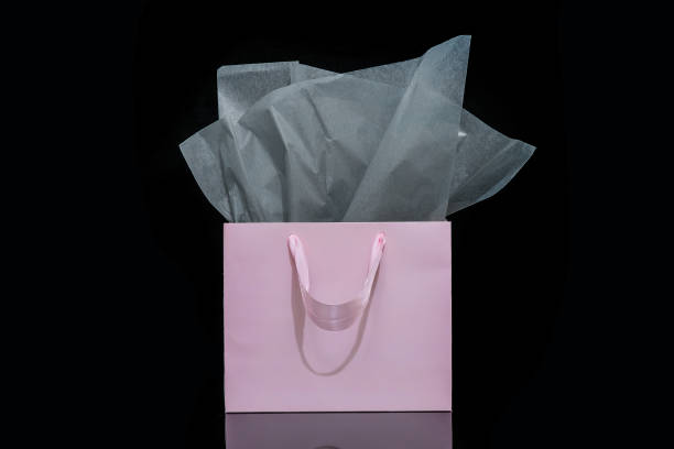 istock Craft paper gift bag with tissue paper isolated on a black background 1482180445