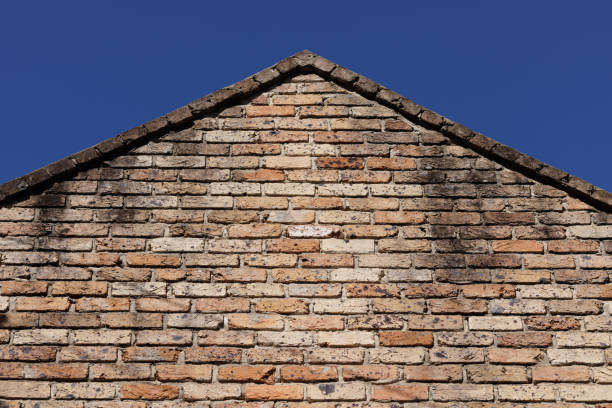 Looking up at the top of an old brick wall.