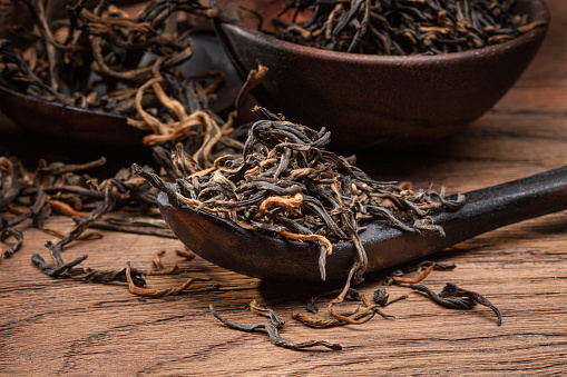 Scoop of dry tea. Dried tea leaves. Wooden scoop and dried tea leaves, close up. Shallow depth of field