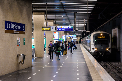 Puteaux, France - April 9, 2023: Passengers get ready to board the train arriving at the platform in La Defense - Grande Arche underground station on Line A of the RER public transportation network.