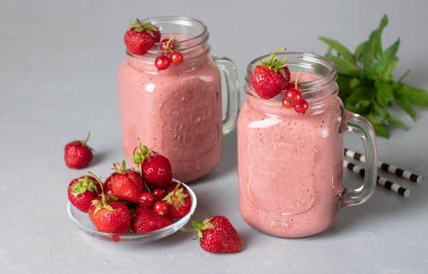 Protein cocktail of strawberries, red currant, yogurt and honey on light gray background stock photo