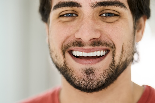 Close-up face portrait of smiling young man with healthy white teeth
