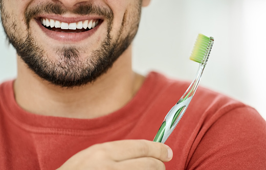 Cropped shot of a happy male face smiling with clean teeth holding a toothbrush