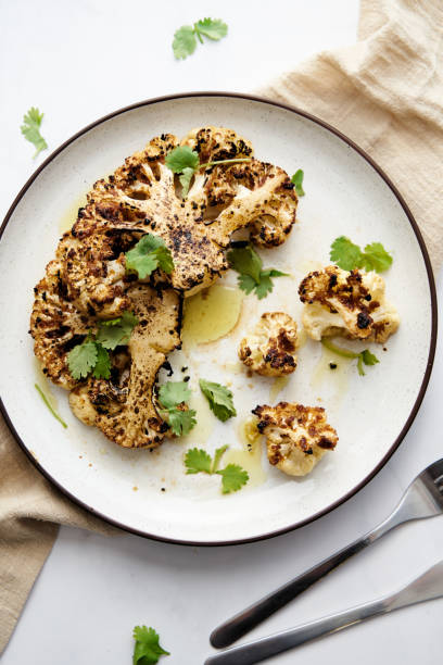 istock Baked cauliflower steak on white plate with cilantro leaves 1482186508