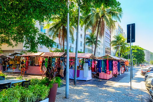 Rio de Janeiro, Brazil - April 4, 2023: A residential district in the Copacabana beach. Many colorful souvenirs stands under some lush trees.