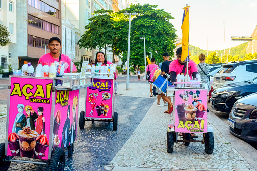 Rio de Janeiro, Brazil - April 4, 2023: A small group of young people pushes food-selling carts reading 