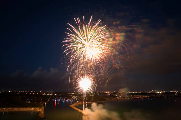 Aerial view of bright fireworks exploding with colorful lights over sea shore on US Independence day holiday
