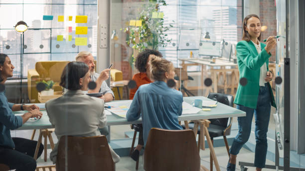 istock A Young Caucasian Woman Presenting Statistics on Funding Using Charts and Whiteboard. A Female Analyst Discussing Data in Office Meeting with Multiethnic Diverse Group 1482196917