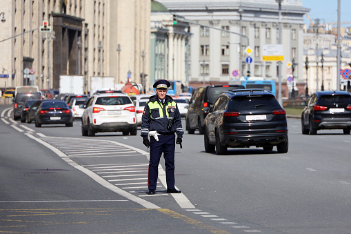 Moscow, Russia - April 2023: Traffic police officer standing against cars and State Duma building. Policeman patrol the city street in center of Moscow