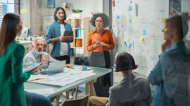 istock Diverse Modern Office: Successful Black Female Digital Entrepreneur Uses Whiteboard with Big Data, Statistics, Talks about Company Growth, Discusses Strategy with Investors, Top Managers, Executives 1482197461