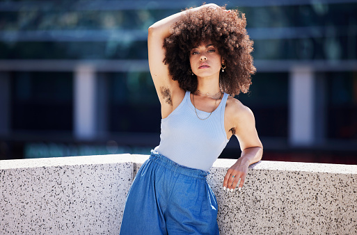 Portrait, fashion and armpit with a black woman in the city on a bridge, looking relaxed during summer. Street, style or urban and a natural young female posing outside with an afro hairstyle