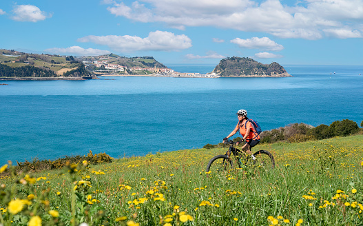 nice senior woman cycling with her electric mountain bike in the hills above Zarautz, Basque Country, Spain