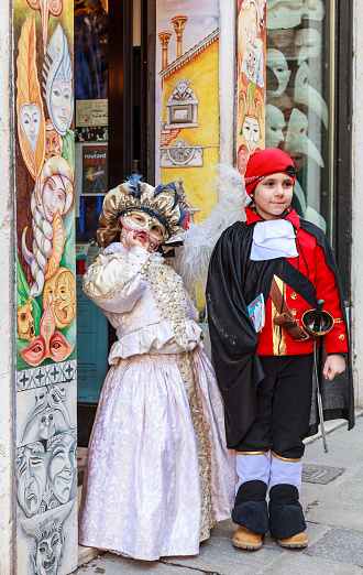 Venice, Italy- February 18, 2012: Image of a disguised couple of children posing in front of a traditional shop, during the Venice Carnival days.