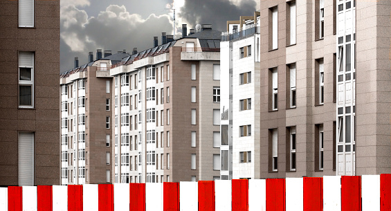 Modern tall apartment buildings in a row . Striped red  and white fence in the foreground. Lugo city, Galicia, Spain.